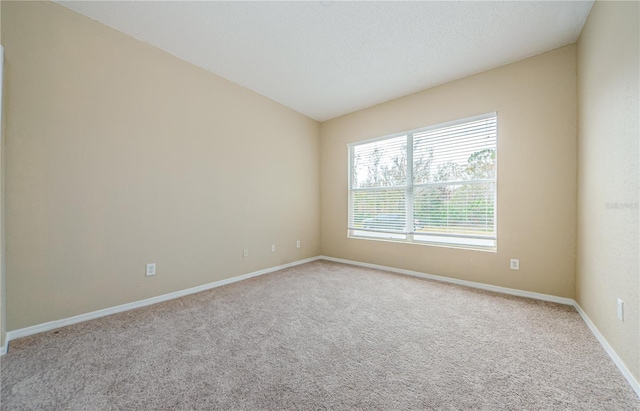 carpeted empty room featuring lofted ceiling