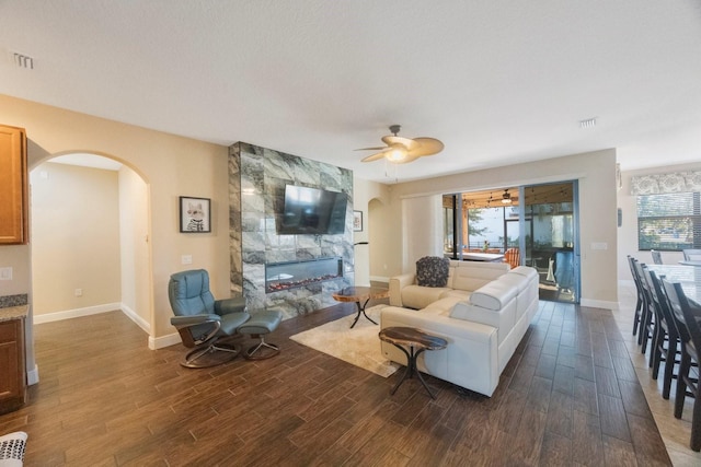 living room featuring a tiled fireplace and ceiling fan