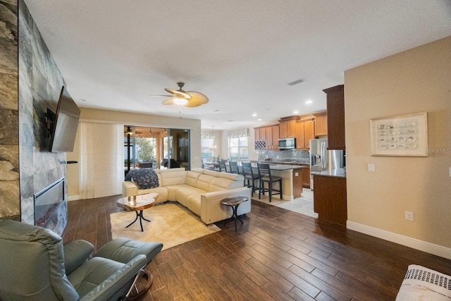 living room featuring ceiling fan and a tiled fireplace