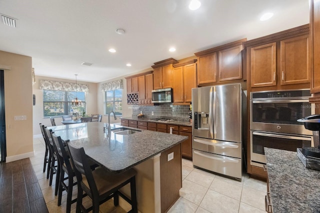 kitchen featuring sink, decorative light fixtures, a kitchen breakfast bar, stainless steel appliances, and a kitchen island with sink