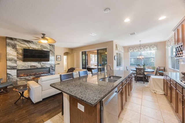 kitchen with sink, hanging light fixtures, plenty of natural light, a center island with sink, and stainless steel dishwasher