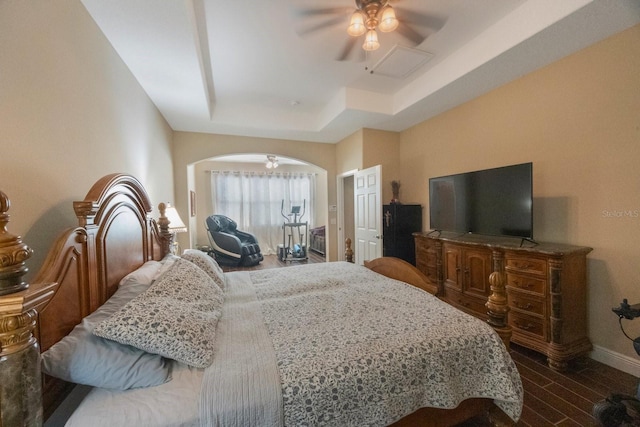 bedroom with hardwood / wood-style flooring, ceiling fan, and a tray ceiling