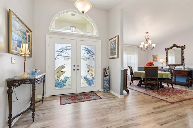 foyer entrance featuring light hardwood / wood-style floors, french doors, and a chandelier