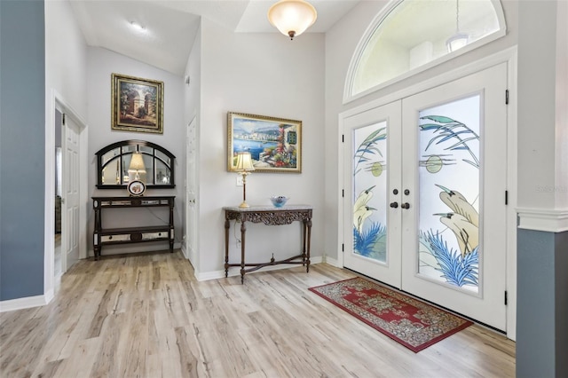 entrance foyer with a towering ceiling, light hardwood / wood-style flooring, and french doors