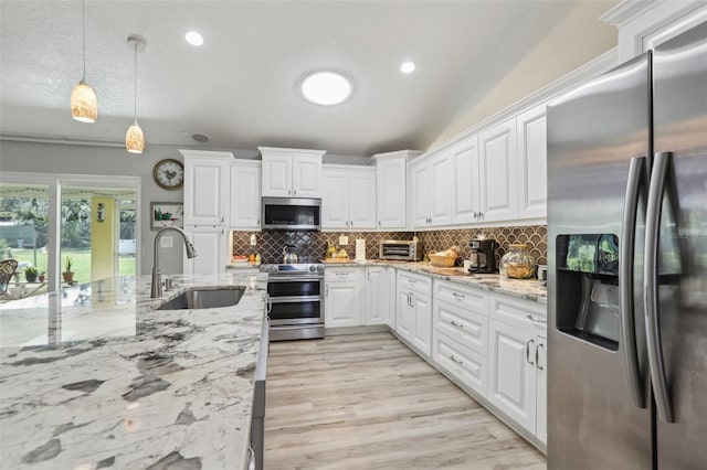 kitchen with pendant lighting, tasteful backsplash, white cabinetry, sink, and stainless steel appliances