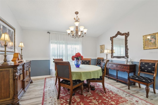 dining area with light hardwood / wood-style floors, a chandelier, and vaulted ceiling