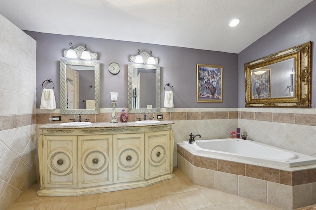 bathroom with tiled tub, vanity, tile walls, and tile patterned floors