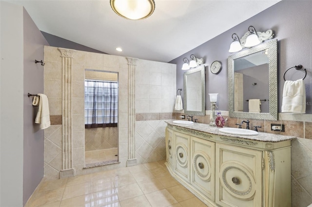 bathroom with tile patterned flooring, vanity, lofted ceiling, and tile walls