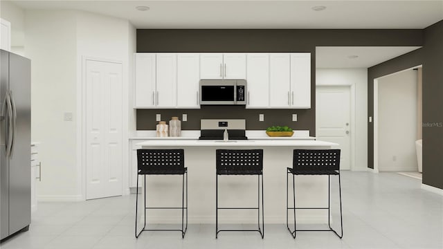 kitchen featuring light tile patterned flooring, stainless steel appliances, a kitchen bar, and white cabinets