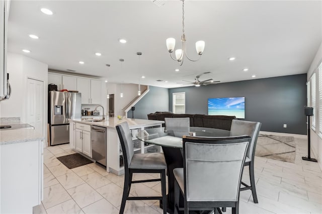 dining area with ceiling fan with notable chandelier and sink