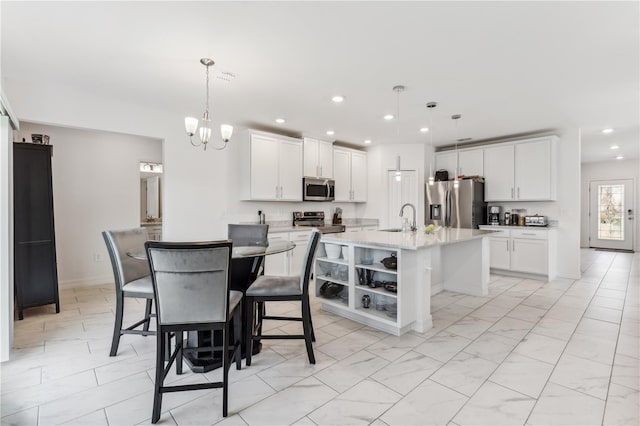 kitchen featuring white cabinetry, an island with sink, appliances with stainless steel finishes, and pendant lighting