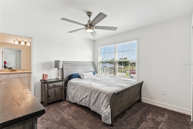 bedroom featuring ceiling fan, ensuite bathroom, sink, and dark carpet