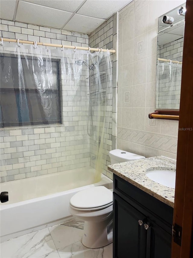 full bathroom featuring a paneled ceiling, tile walls, vanity, toilet, and shower / bathtub combination with curtain