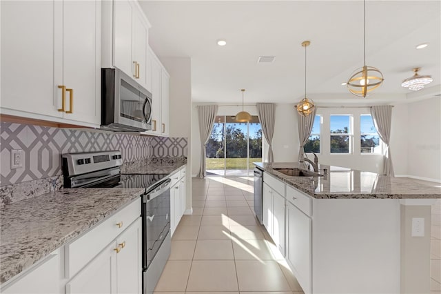 kitchen with sink, white cabinetry, decorative light fixtures, stainless steel appliances, and a kitchen island with sink