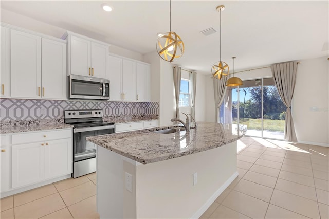 kitchen with appliances with stainless steel finishes, white cabinetry, sink, hanging light fixtures, and a center island with sink