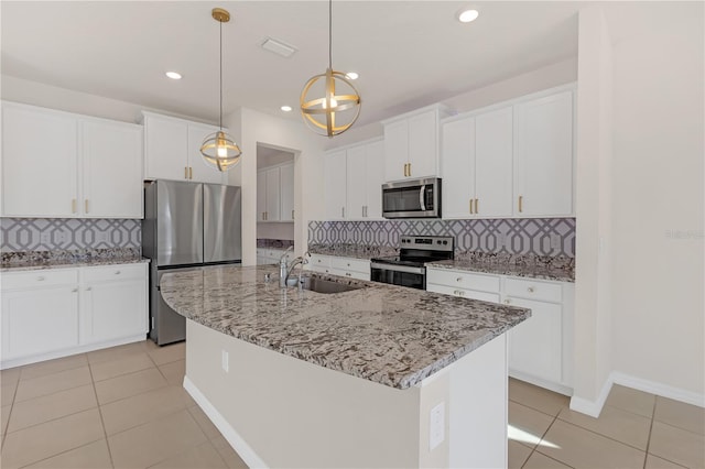 kitchen with pendant lighting, sink, white cabinets, a kitchen island with sink, and stainless steel appliances