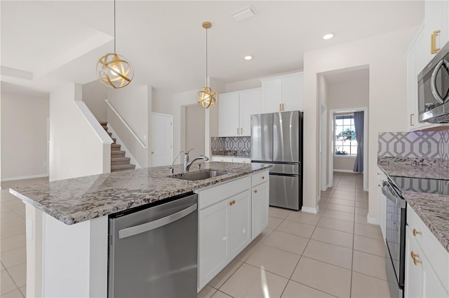 kitchen with white cabinetry, stainless steel appliances, sink, and a center island with sink