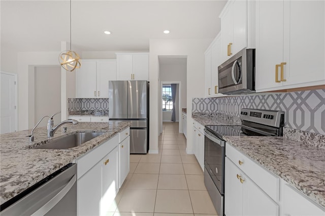 kitchen with light tile patterned flooring, appliances with stainless steel finishes, white cabinetry, sink, and hanging light fixtures