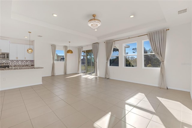 unfurnished living room with light tile patterned floors and a raised ceiling