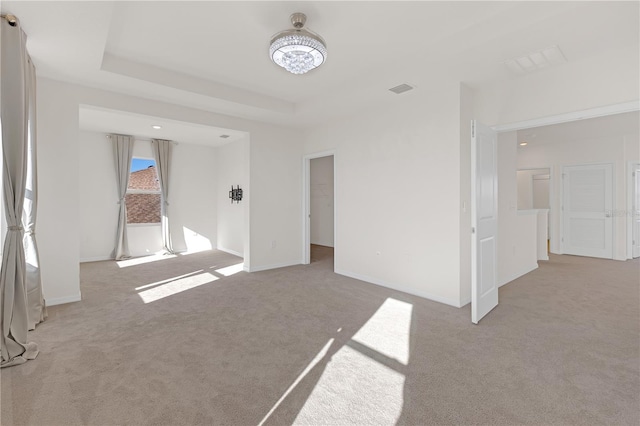 spare room with light carpet and a tray ceiling