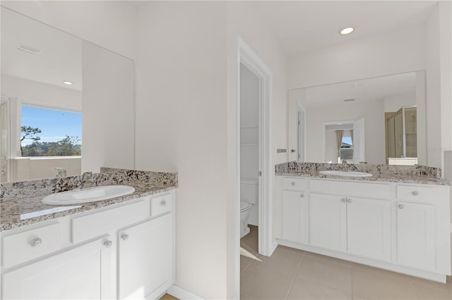 bathroom featuring vanity, toilet, a shower with shower door, and tile patterned flooring