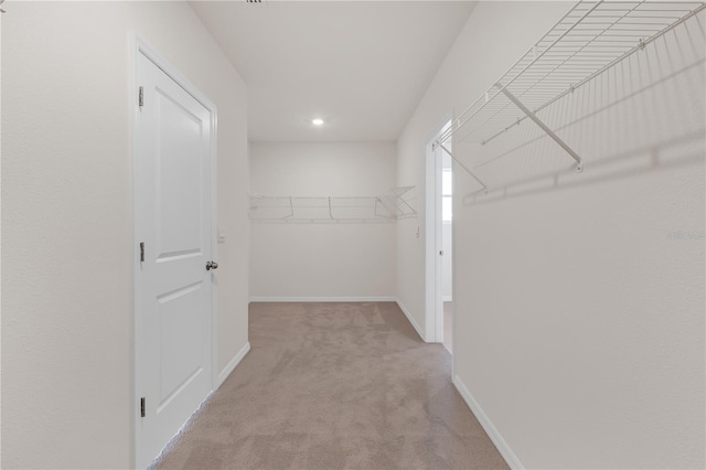 walk in closet with light colored carpet