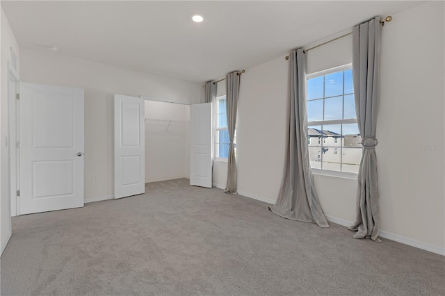 unfurnished bedroom with multiple windows, light carpet, and a closet