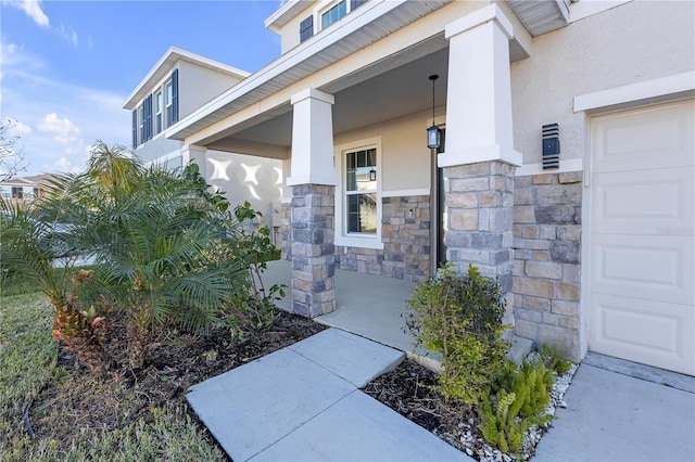 view of exterior entry with a porch and a garage