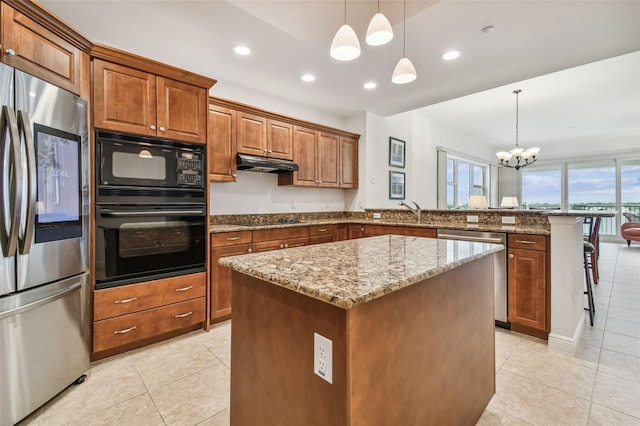 kitchen with decorative light fixtures, a center island, a breakfast bar area, and black appliances