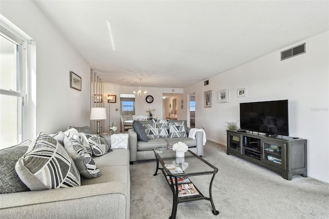 carpeted living room featuring a chandelier