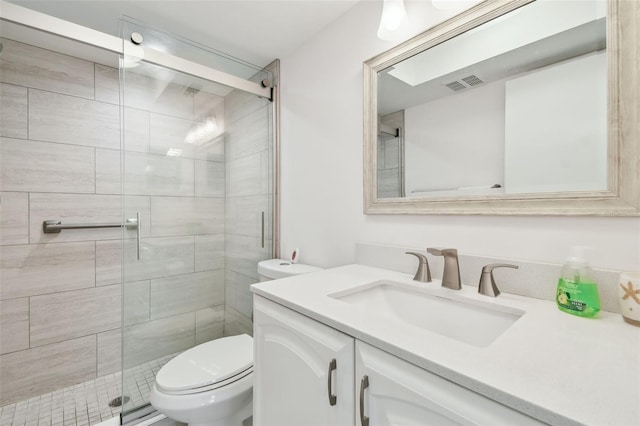 bathroom featuring vanity, a shower with door, and toilet