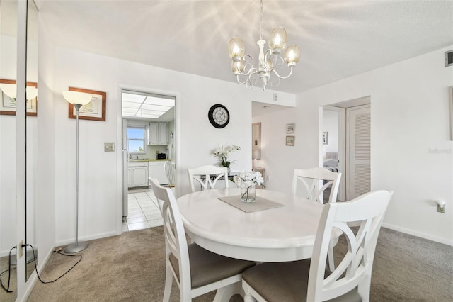 dining room featuring light colored carpet, a notable chandelier, and a textured ceiling