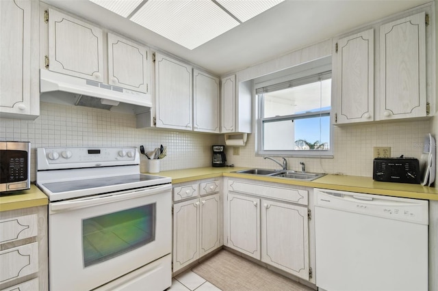 kitchen with sink, white appliances, white cabinets, and backsplash