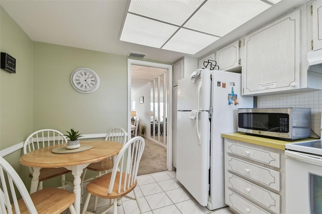 kitchen featuring white cabinetry, white appliances, light tile patterned flooring, and backsplash