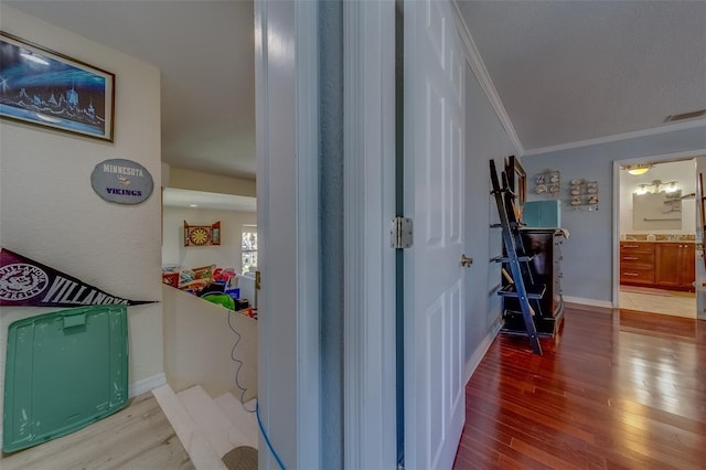 hallway with ornamental molding and light hardwood / wood-style flooring