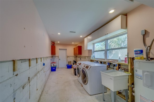 washroom with independent washer and dryer, sink, and water heater