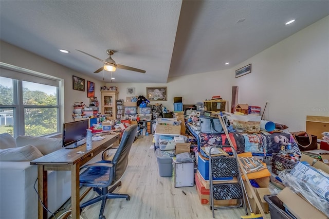 home office with ceiling fan, light hardwood / wood-style flooring, and a textured ceiling