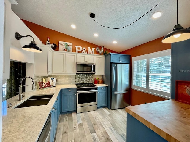 kitchen featuring pendant lighting, white cabinetry, sink, stainless steel appliances, and blue cabinetry