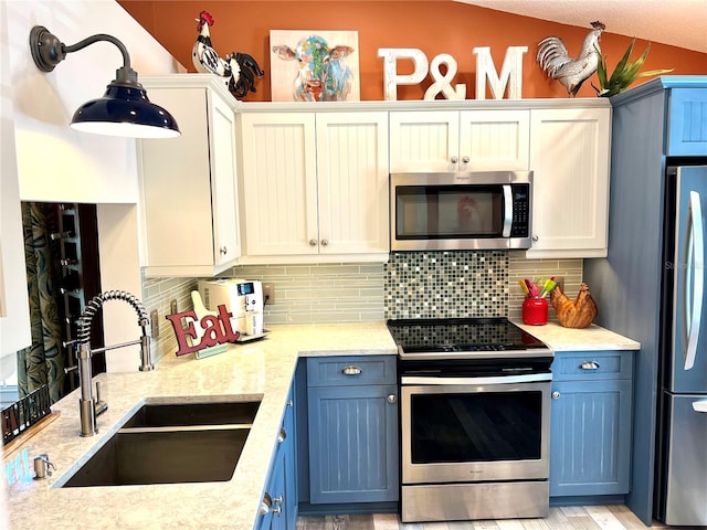 kitchen with appliances with stainless steel finishes, white cabinetry, sink, decorative backsplash, and blue cabinetry