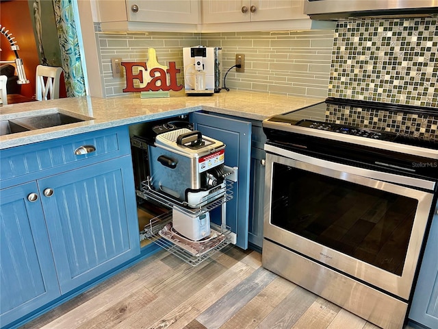 kitchen featuring blue cabinets, tasteful backsplash, sink, light hardwood / wood-style floors, and electric stove