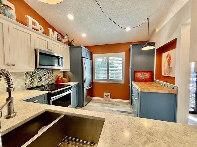 kitchen with butcher block countertops, white cabinetry, decorative light fixtures, stainless steel appliances, and decorative backsplash