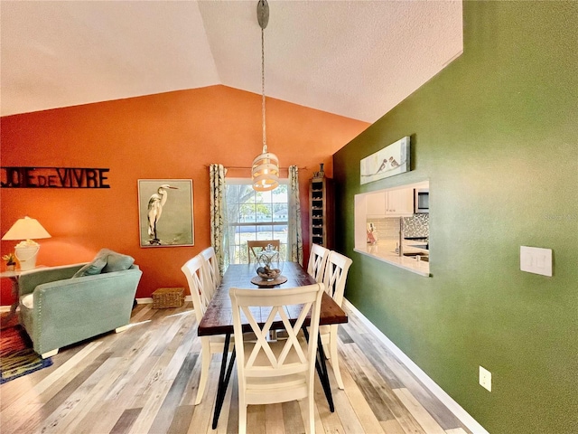 dining area with vaulted ceiling and light wood-type flooring