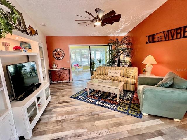 living room with vaulted ceiling, hardwood / wood-style floors, ceiling fan, and a textured ceiling