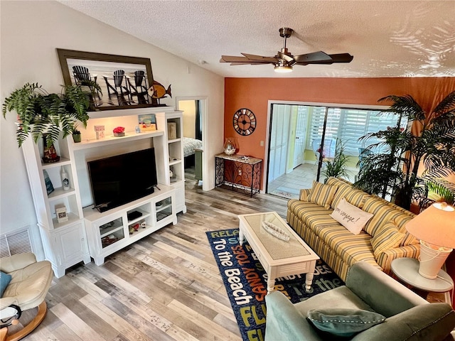 living room with ceiling fan, hardwood / wood-style flooring, vaulted ceiling, and a textured ceiling