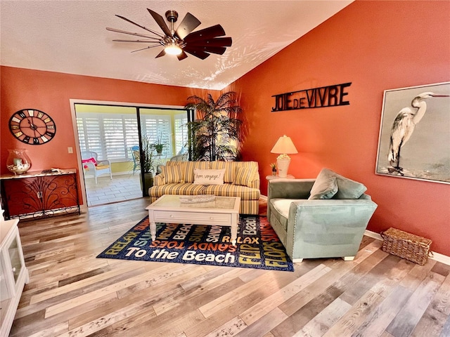 living room with vaulted ceiling, wood-type flooring, ceiling fan, and a textured ceiling