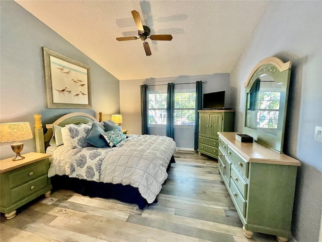 bedroom with ceiling fan, lofted ceiling, light hardwood / wood-style flooring, and a textured ceiling