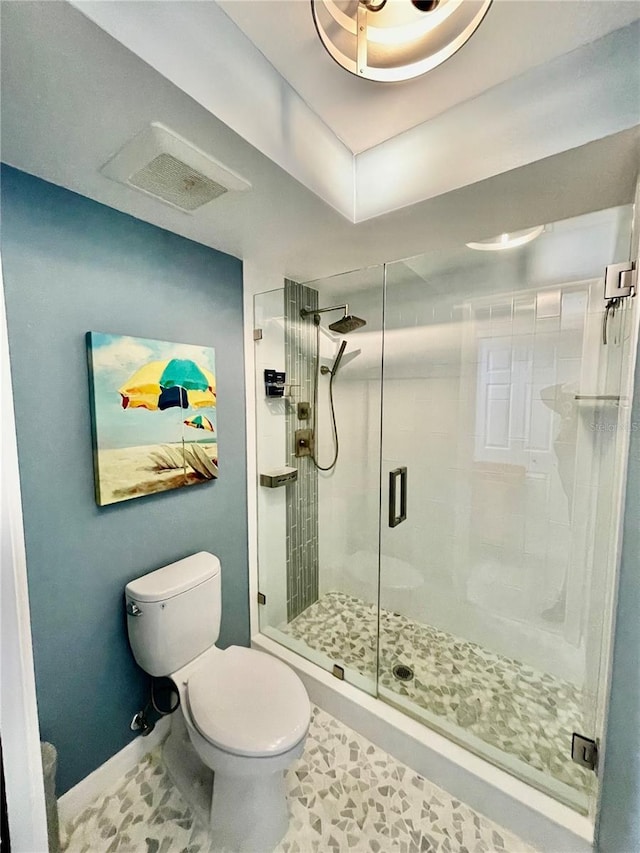 bathroom with tile patterned floors, toilet, and a shower with door