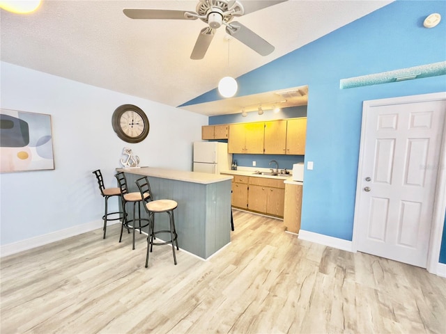 kitchen with lofted ceiling, a breakfast bar, light hardwood / wood-style flooring, kitchen peninsula, and white fridge