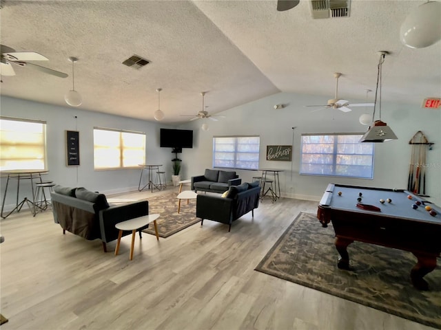 playroom featuring lofted ceiling, a wealth of natural light, a textured ceiling, and light wood-type flooring