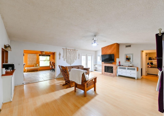 living room with a textured ceiling, a wealth of natural light, lofted ceiling, and light hardwood / wood-style floors